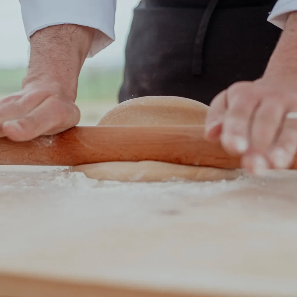 Rolling fresh pasta dough with a rolling pin during a cooking class